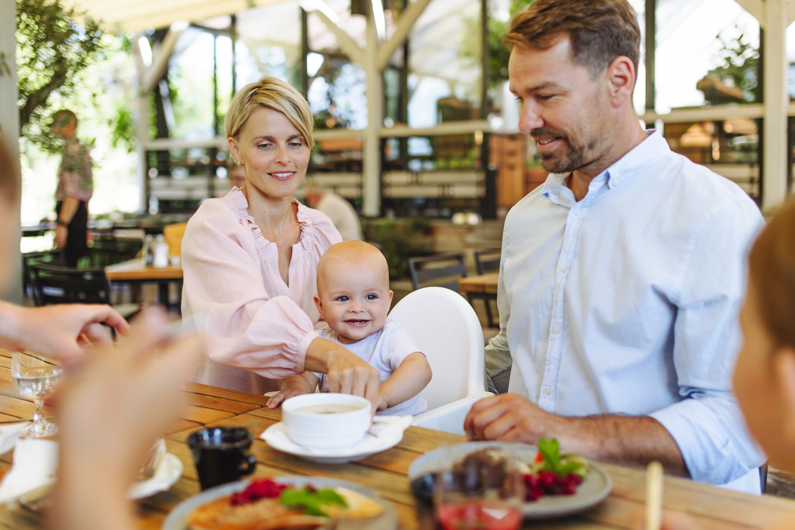family with baby in high chair eating food at restaurant.
